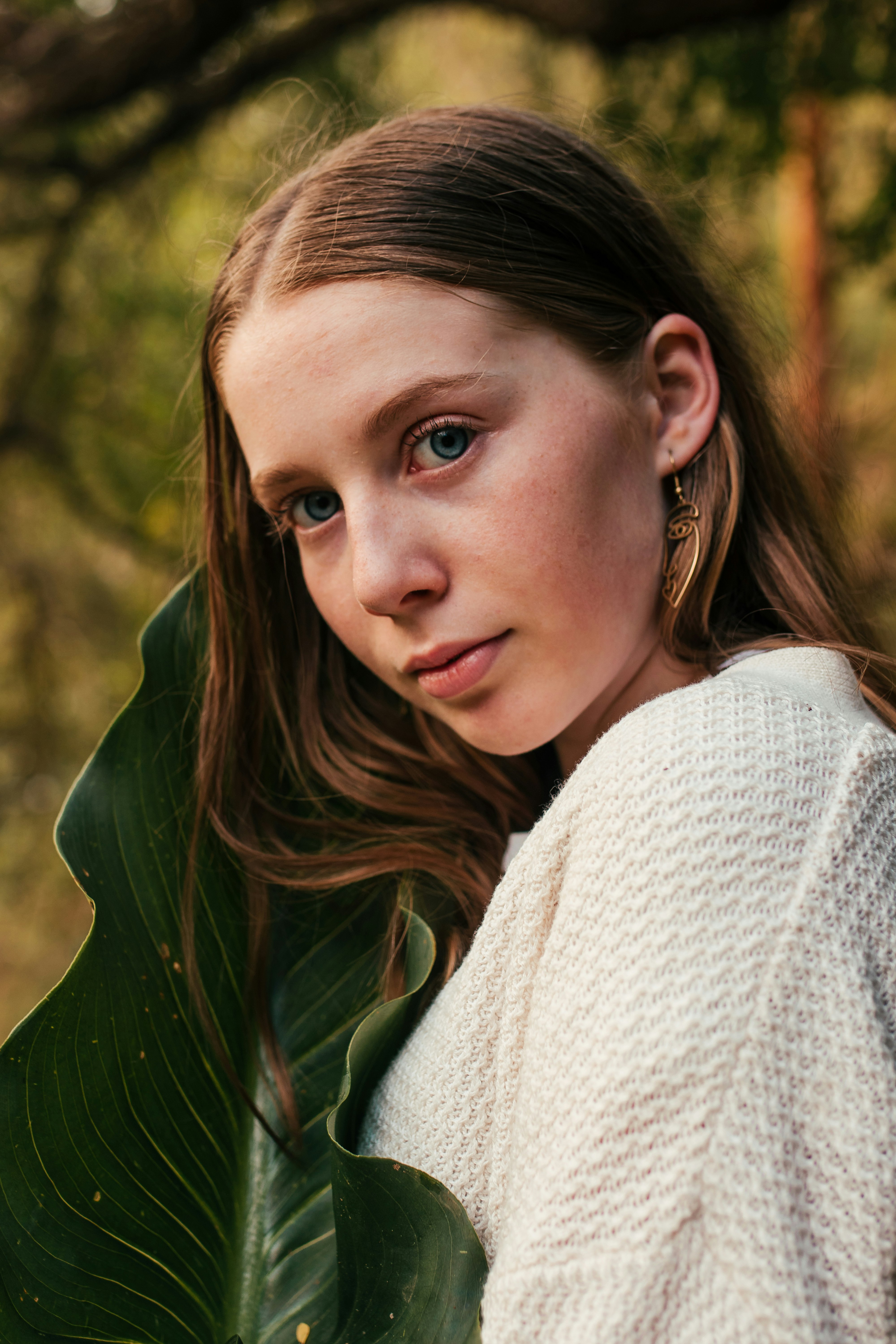 woman wearing white crew-neck sweater standing near green leaf plant glancing her right side